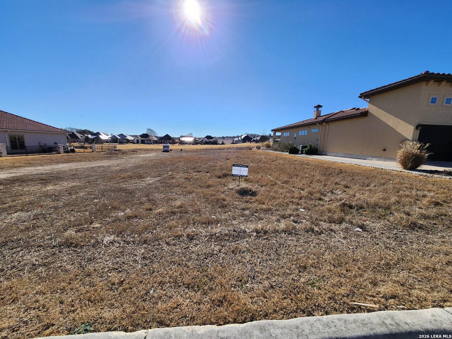 a view of a dry yard with wooden fence