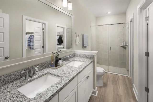 a bathroom with a granite countertop sink a mirror a toilet and shower