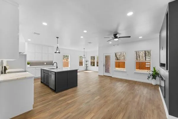 a large white kitchen with wooden floors and stainless steel appliances