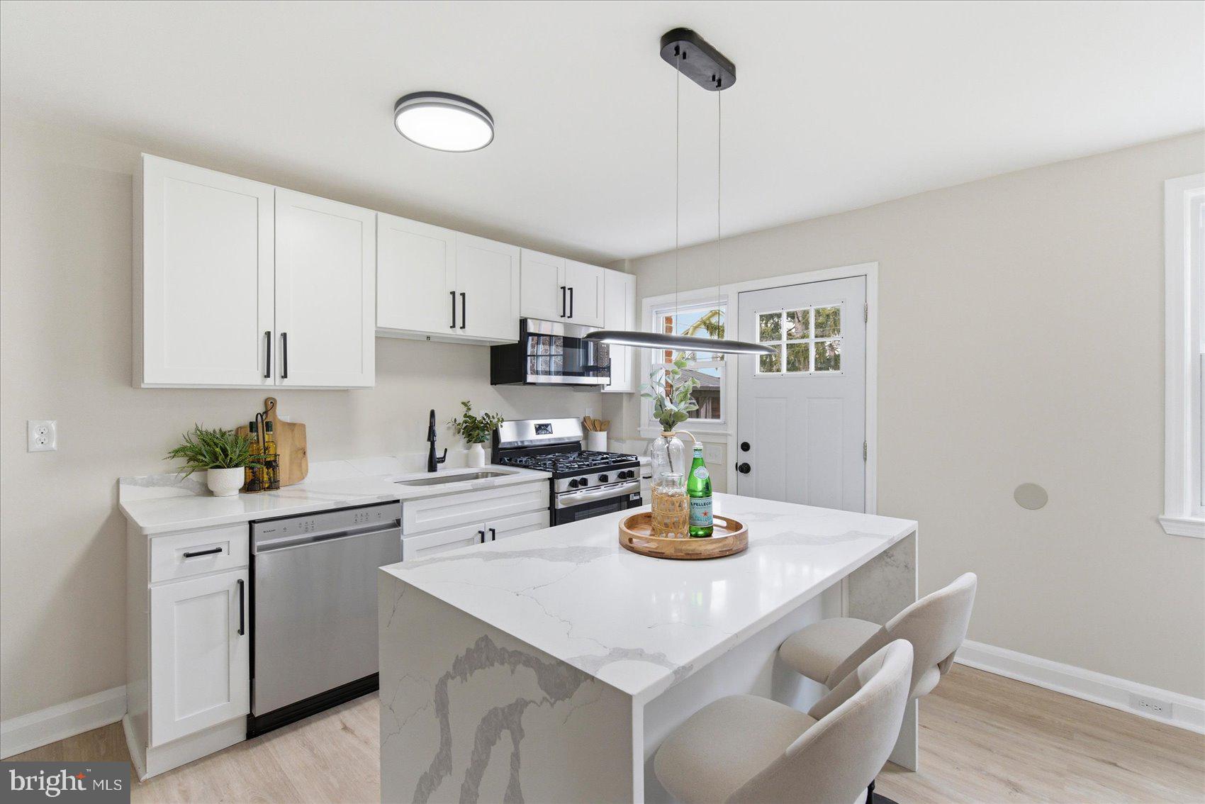 10 Mardrew Road Baltimore, MD 21229 - Photo 13 of 37 a kitchen with a sink a stove and white cabinets with wooden floor