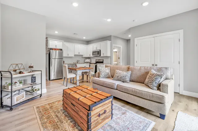 a living room with furniture and a dining table with kitchen appliances