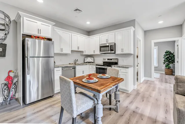 a kitchen with a refrigerator a stove a sink dishwasher and white cabinets with wooden floor