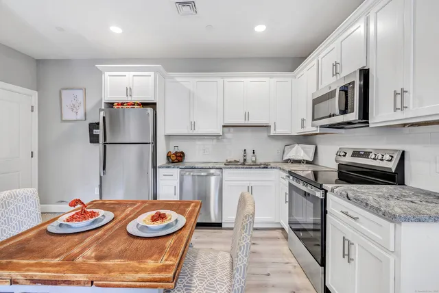 a kitchen with stainless steel appliances granite countertop a sink stove and refrigerator