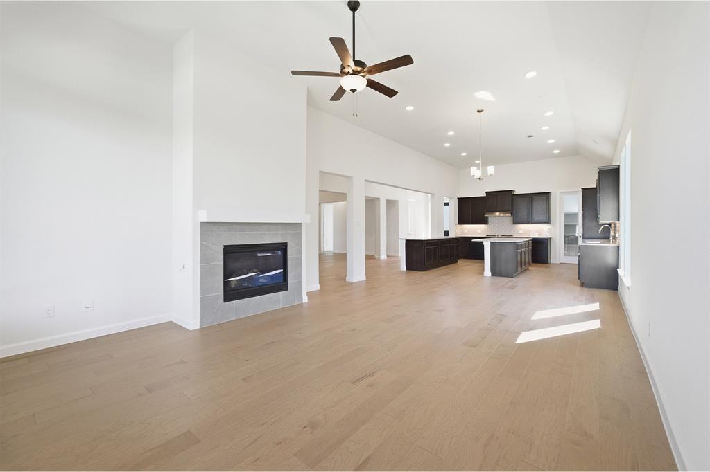 2020 Casting Ridge Mesquite, TX 75181 - Photo 14 of 34 Open-concept living area featuring light wood-finish flooring, a contemporary fireplace with a tile surround, a dark wood-finish ceiling fan, and recessed lighting
