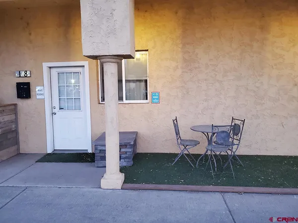 a patio with table and chairs and potted plants