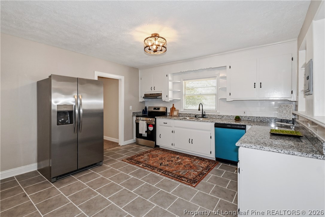5307 Cypress Road Fayetteville, NC 28304 - Photo 15 of 36 a kitchen with granite countertop a refrigerator a stove a sink a counter space and cabinets