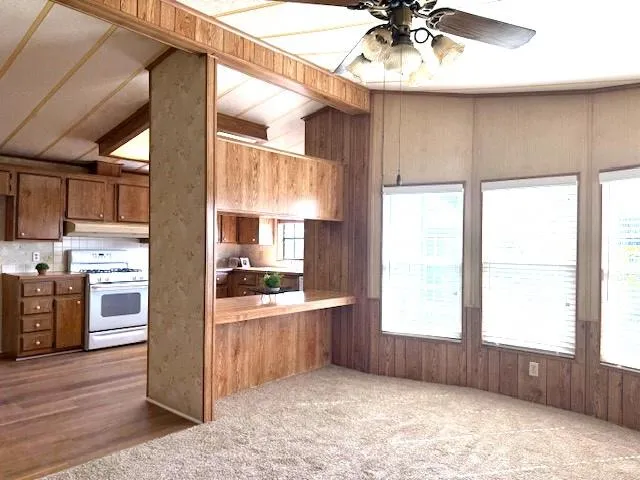 a kitchen with stainless steel appliances kitchen island granite countertop a refrigerator a sink dishwasher a stove and a dining table with wooden cabinet