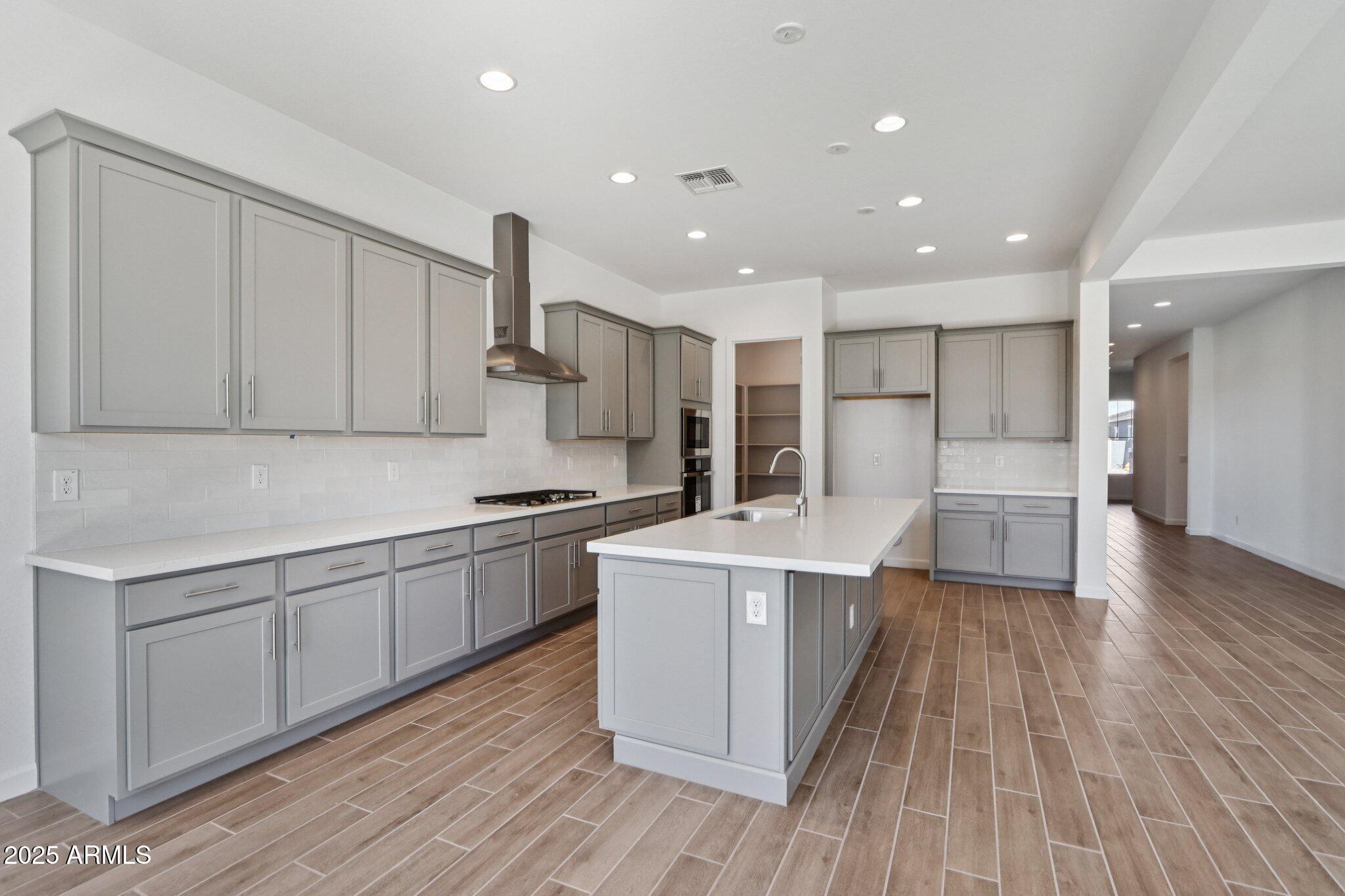 11417 East Utah Avenue Mesa, AZ 85212 - Photo 12 of 55 a kitchen with stainless steel appliances kitchen island wooden floors and white cabinets