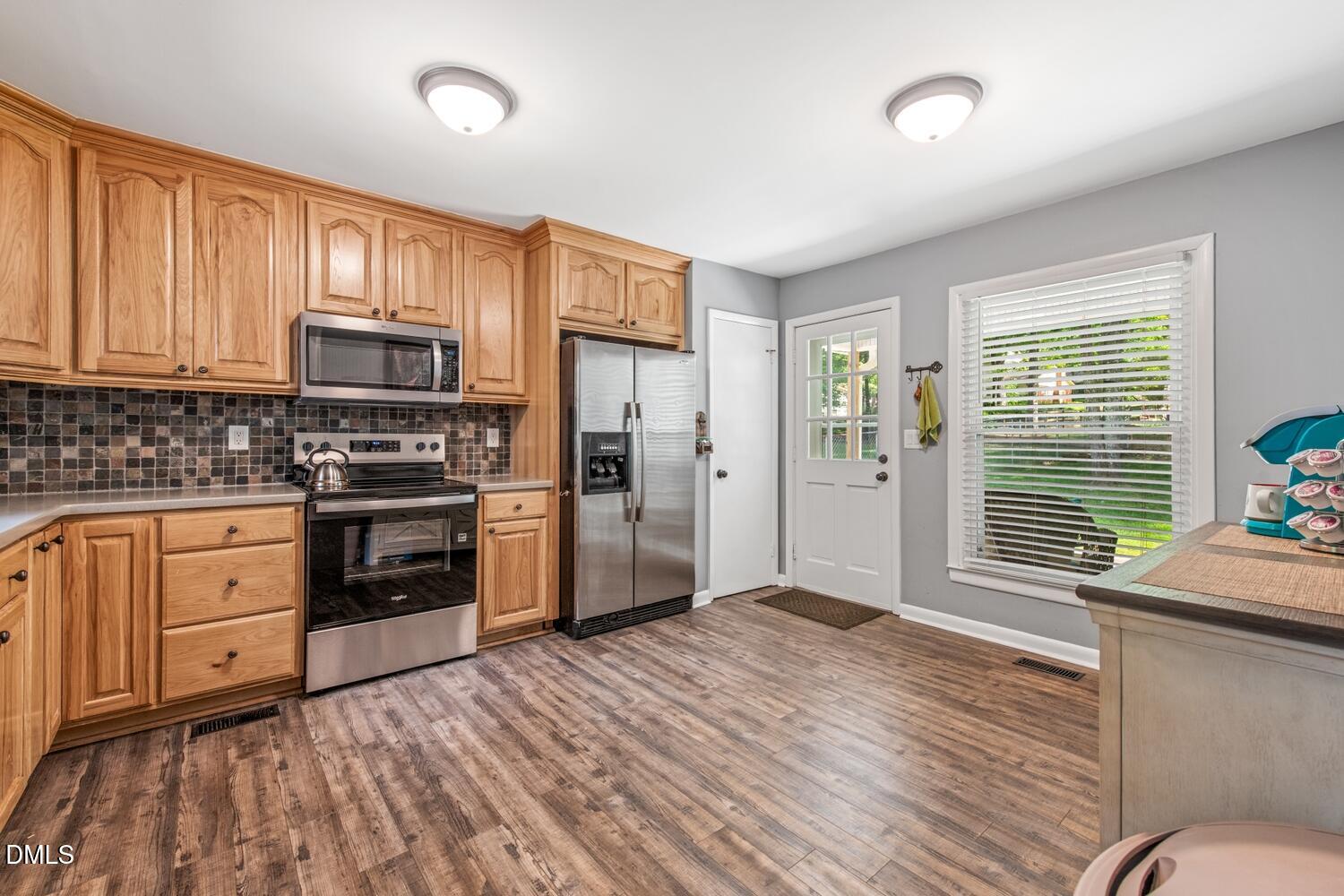 134 Longview Road Madison, NC 27025 - Photo 11 of 49 a kitchen with granite countertop wooden floors stainless steel appliances and window