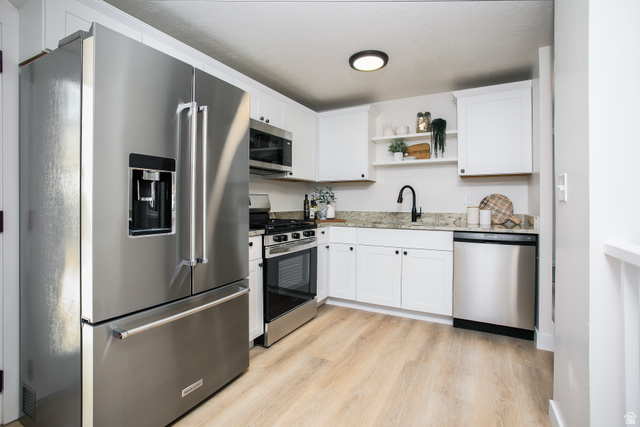 621 Timpie Road Tooele, UT 84074 - Photo 5 of 16 Full kitchen featuring stainless steel appliances, white cabinetry with dark hardware, stone countertops, and wood-finish flooring