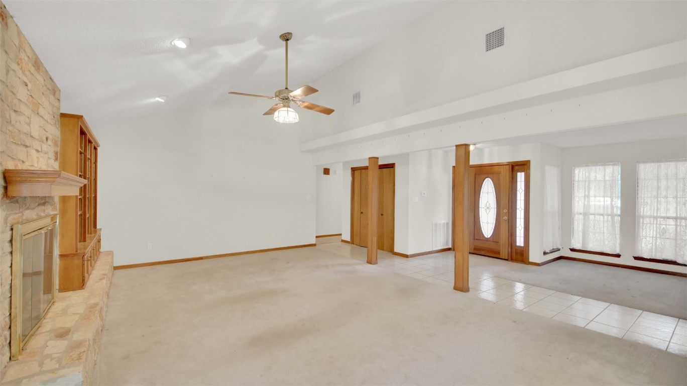 1403 Stone Ridge Drive Taylor, TX 76574 - Photo 11 of 39 Unfurnished living room with light carpet, a ceiling fan, high vaulted ceiling, light tile patterned flooring, and a stone fireplace