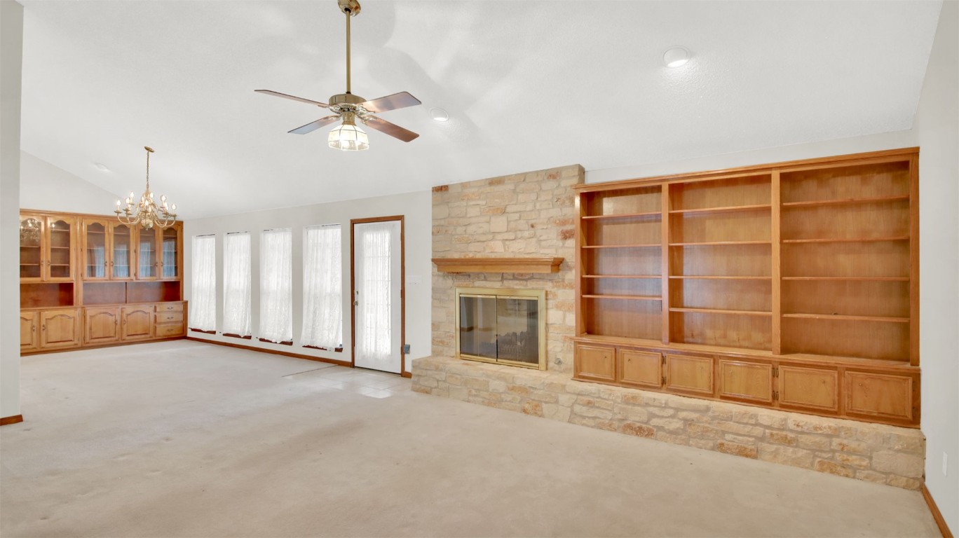 1403 Stone Ridge Drive Taylor, TX 76574 - Photo 13 of 39 Unfurnished living room with carpet flooring, a fireplace, a chandelier, built in features, and ceiling fan