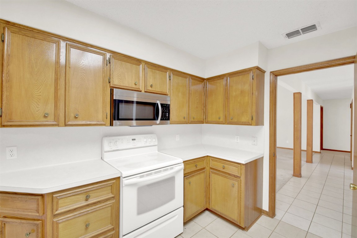 1403 Stone Ridge Drive Taylor, TX 76574 - Photo 18 of 39 Kitchen featuring white electric stove, stainless steel microwave, light countertops, and light tile patterned floors