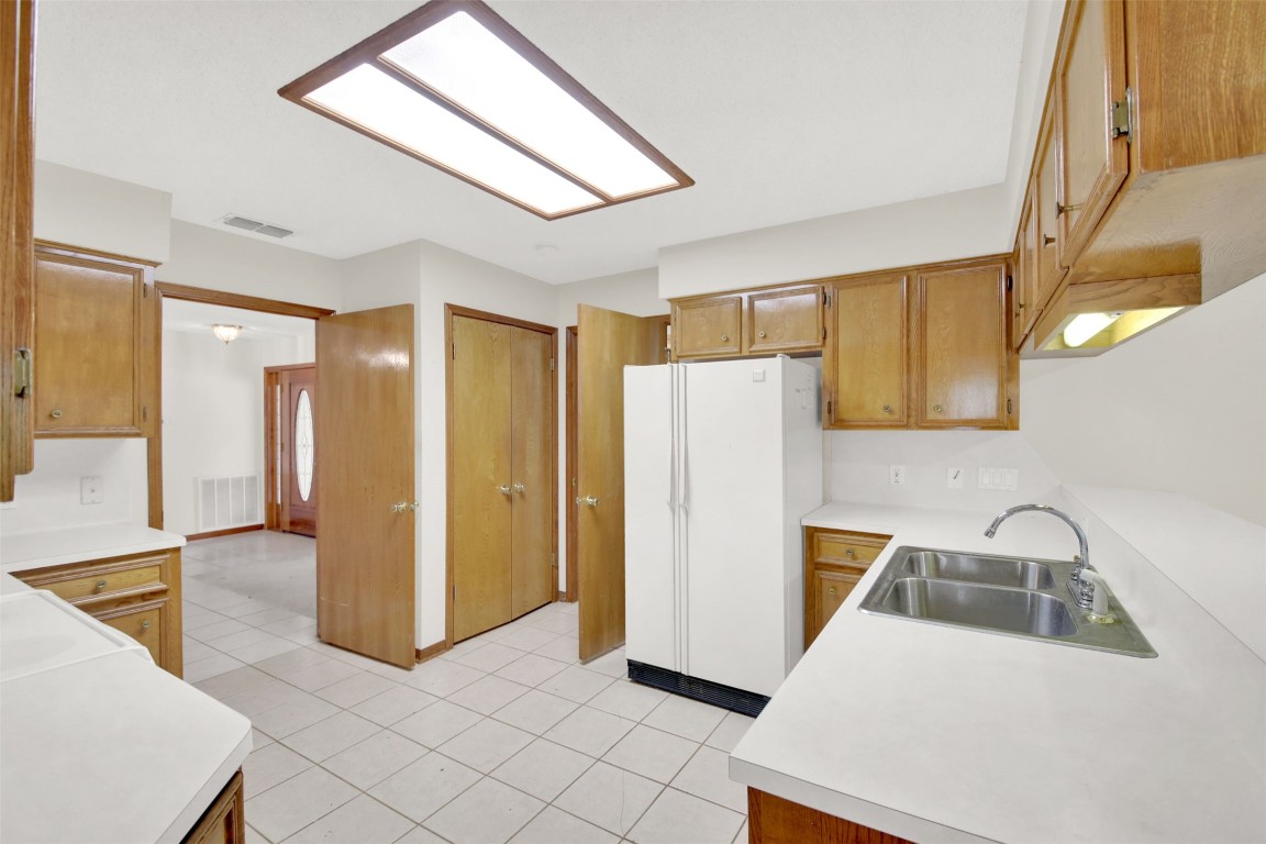 1403 Stone Ridge Drive Taylor, TX 76574 - Photo 19 of 39 Kitchen featuring light countertops, freestanding refrigerator, light tile patterned floors, and brown cabinets