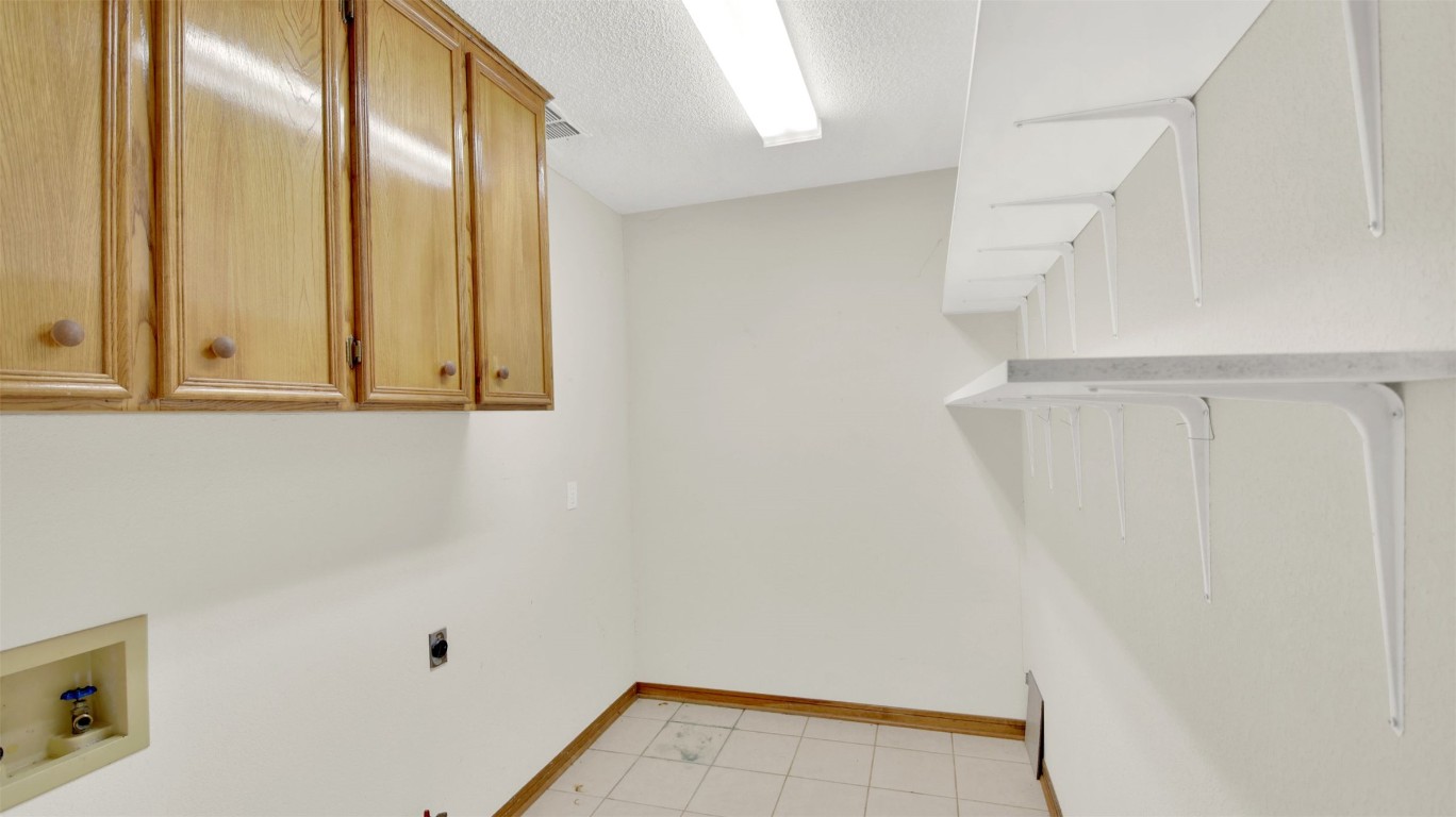 1403 Stone Ridge Drive Taylor, TX 76574 - Photo 22 of 39 Laundry area featuring a textured ceiling, cabinet space, hookup for an electric dryer, light tile patterned floors, and hookup for a washing machine