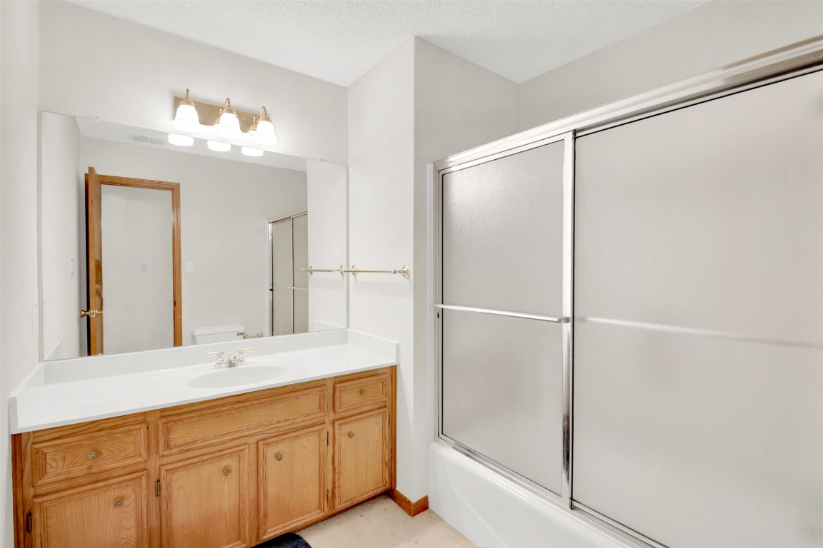 1403 Stone Ridge Drive Taylor, TX 76574 - Photo 25 of 39 Bathroom featuring vanity, combined bath / shower with glass door, and a textured ceiling