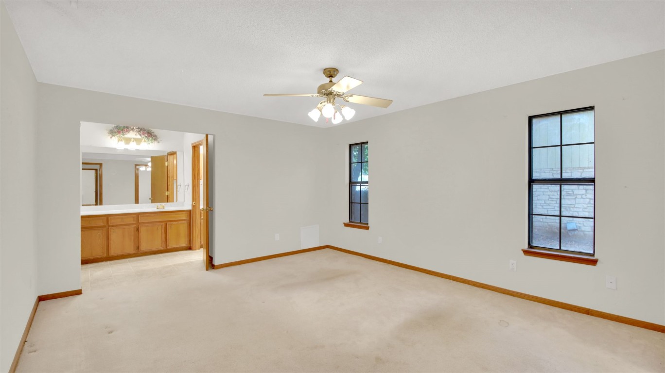1403 Stone Ridge Drive Taylor, TX 76574 - Photo 27 of 39 Unfurnished bedroom featuring light carpet, ceiling fan, and ensuite bathroom