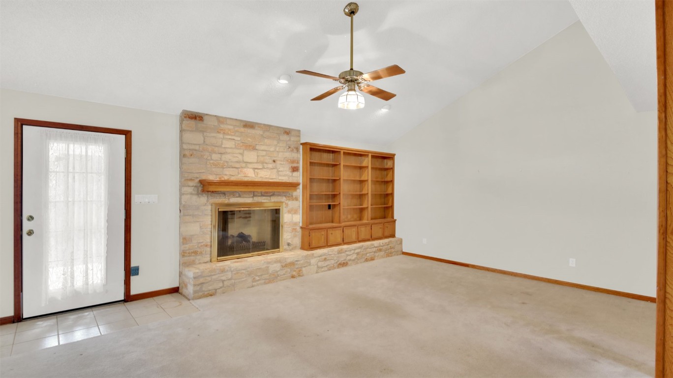 1403 Stone Ridge Drive Taylor, TX 76574 - Photo 9 of 39 Unfurnished living room with carpet, a stone fireplace, a ceiling fan, high vaulted ceiling, and tile patterned floors