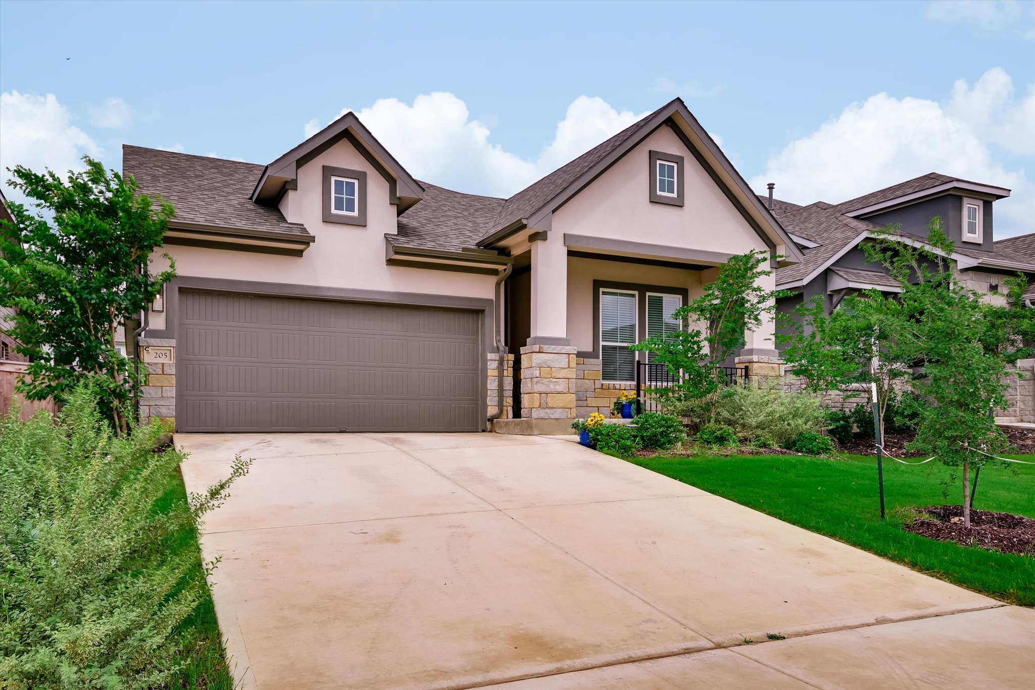 205 Wingstem Way Georgetown, TX 78633 - Photo 4 of 29 Contemporary residential exterior featuring a stucco and stone facade, a gabled roofline, an attached garage, and landscaped front yard.