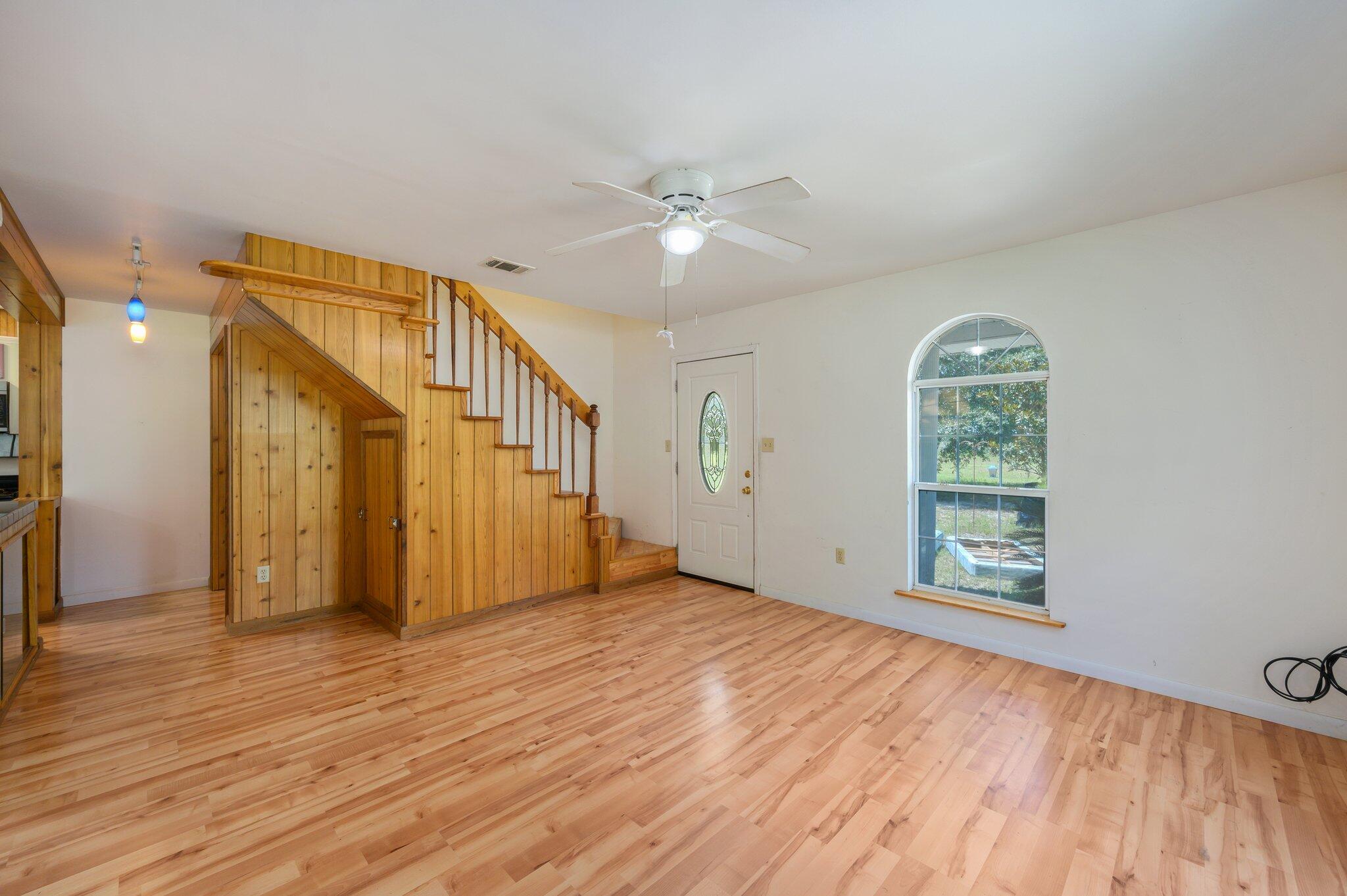 1361 Long Road DeFuniak Springs, FL 32433 - Photo 15 of 43 an empty room with wooden floor chandelier fan and windows