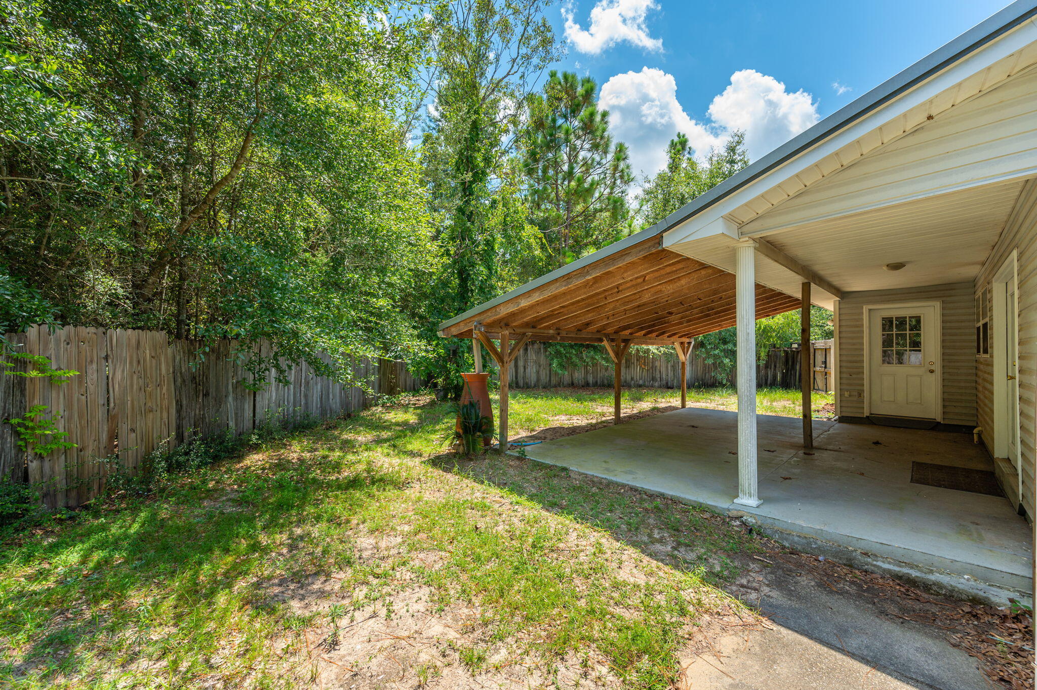 1361 Long Road DeFuniak Springs, FL 32433 - Photo 32 of 43 a backyard of a house with table and chairs under an umbrella