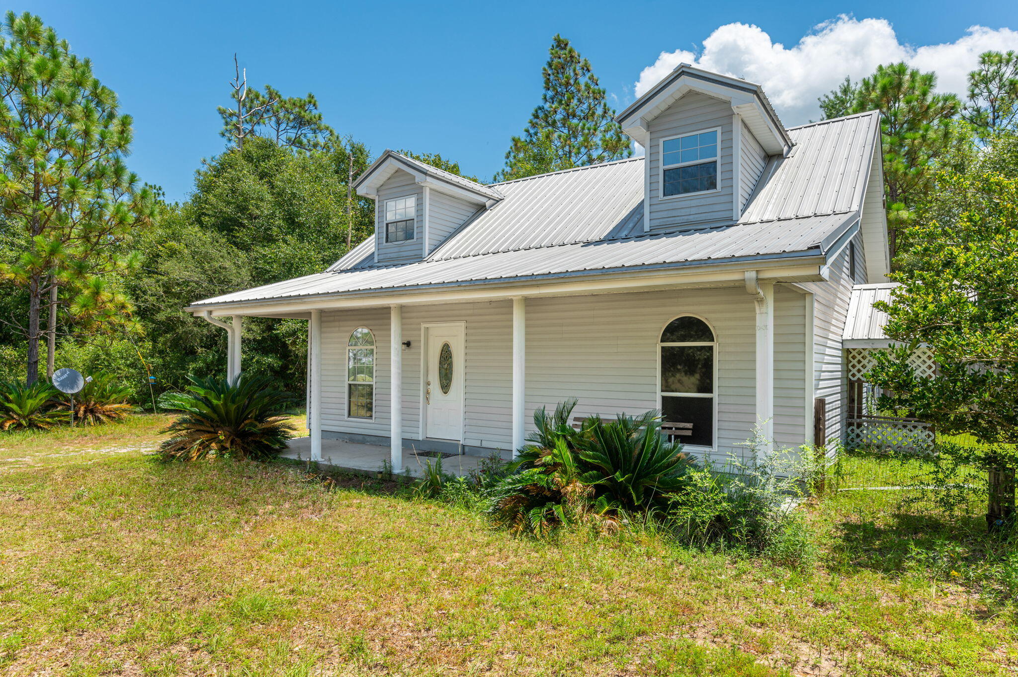 1361 Long Road DeFuniak Springs, FL 32433 - Photo 36 of 43 a view of a white house with large windows plants and large tree