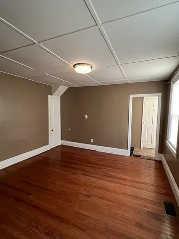 a view of an empty room with window and wooden floor