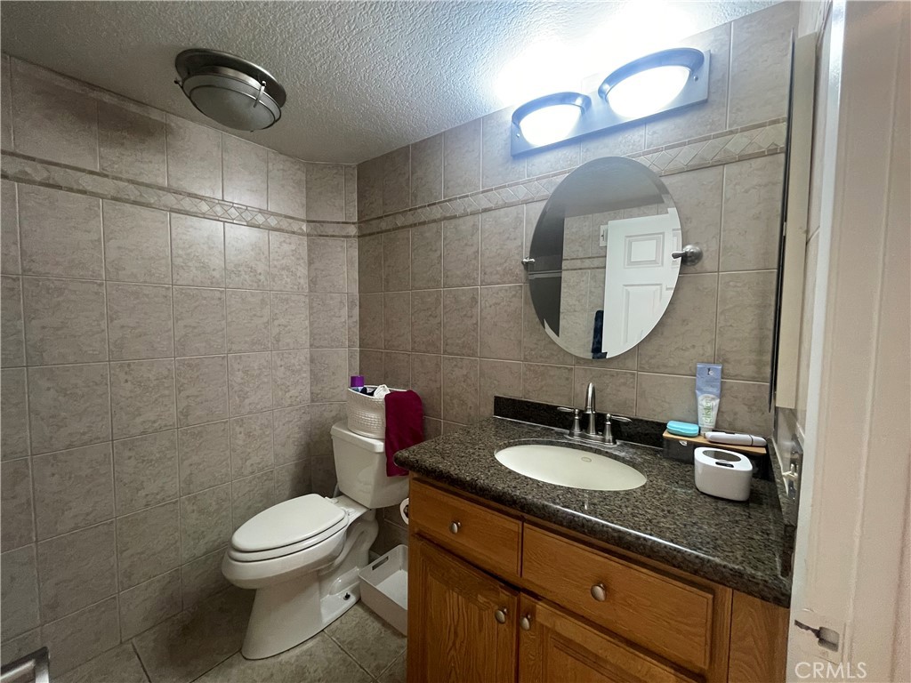 22740 Main Street Grand Terrace, CA 92313 - Photo 13 of 30 a bathroom with a granite countertop sink mirror and toilet