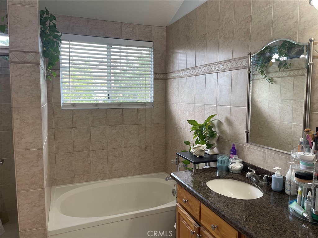 22740 Main Street Grand Terrace, CA 92313 - Photo 20 of 30 a bathroom with a granite countertop sink a toilet and tub