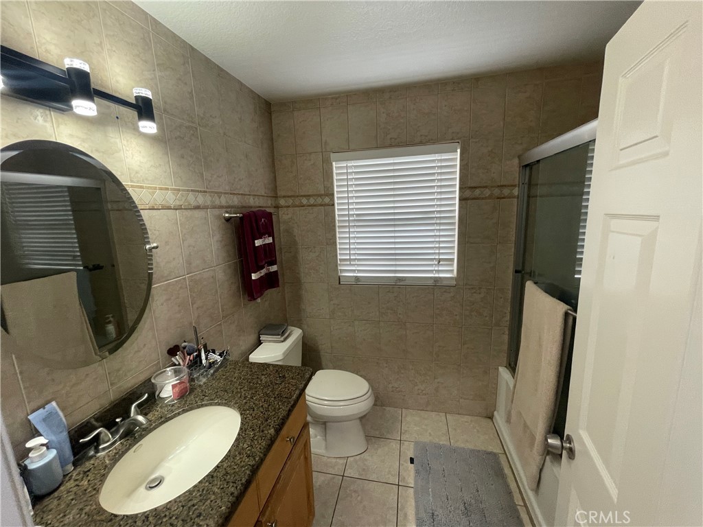 22740 Main Street Grand Terrace, CA 92313 - Photo 24 of 30 a bathroom with a granite countertop sink toilet a mirror and shower