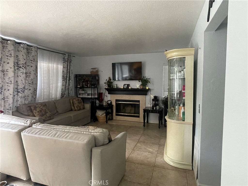 22740 Main Street Grand Terrace, CA 92313 - Photo 7 of 30 a living room with furniture a fireplace and a flat screen tv
