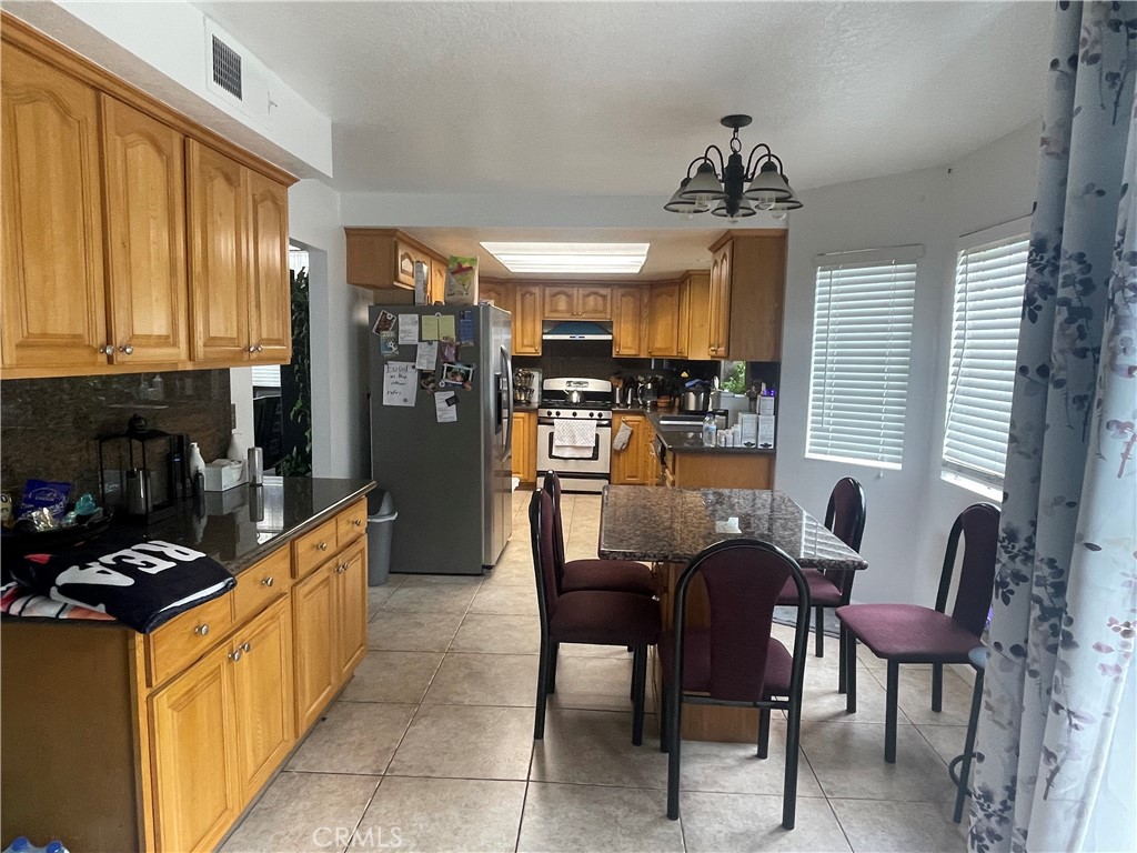 22740 Main Street Grand Terrace, CA 92313 - Photo 9 of 30 a kitchen with stainless steel appliances kitchen island granite countertop a table chairs in it and a window