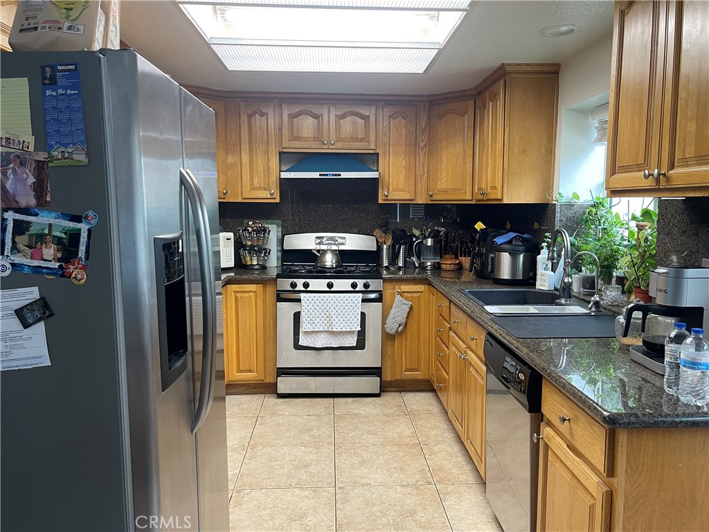 22740 Main Street Grand Terrace, CA 92313 - Photo 10 of 30 a kitchen with stainless steel appliances granite countertop a sink a stove a refrigerator cabinets and a window