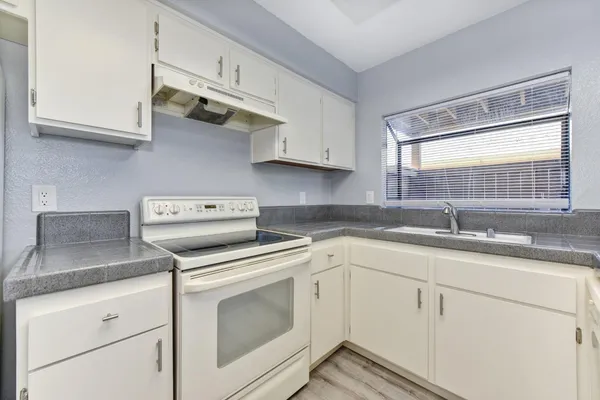 a kitchen with white cabinets and sink
