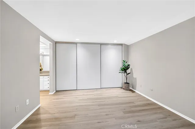 a view of empty room with wooden floor and bathroom