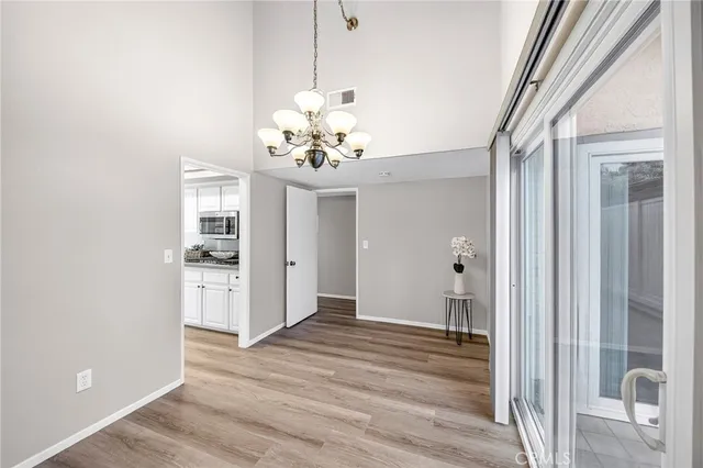 a view of a hallway with wooden floor and a kitchen