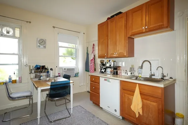 a kitchen with stainless steel appliances a sink a stove cabinets dining table and chairs