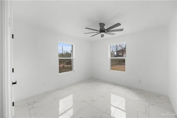 a view of a big room with windows and chandelier fan