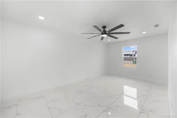 an empty room with chandelier fan and windows