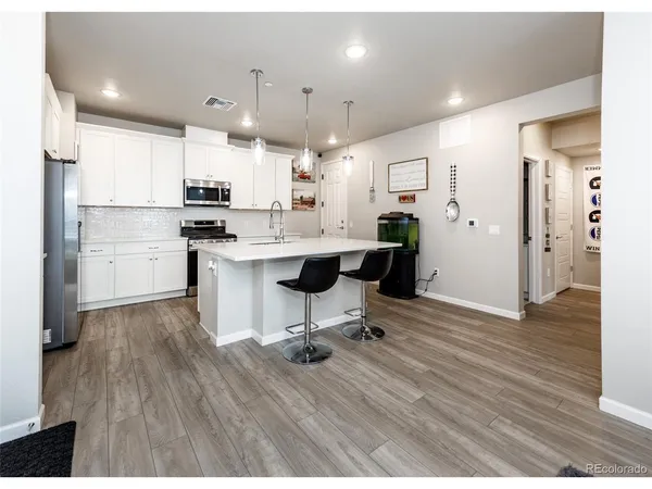 a living room with kitchen island stainless steel appliances furniture wooden floor and view kitchen