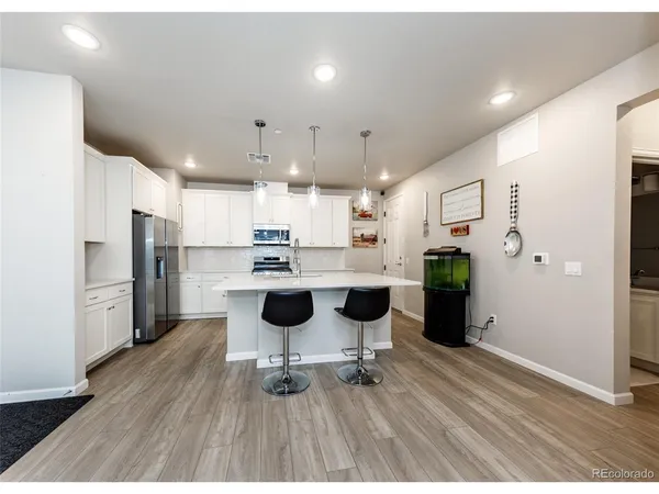 a kitchen with stainless steel appliances a refrigerator and a wooden floor