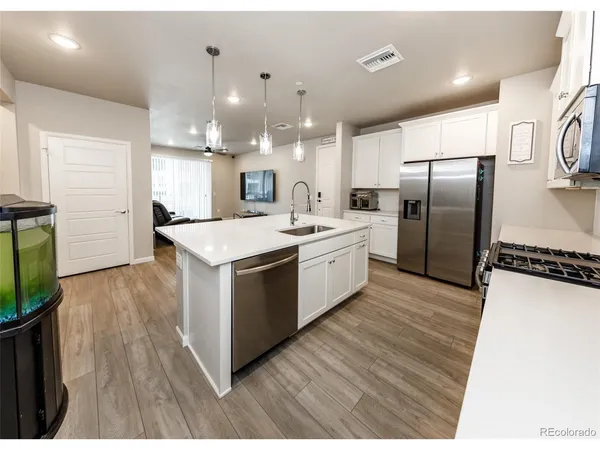 a large kitchen with stainless steel appliances kitchen island a large counter top and wooden floors