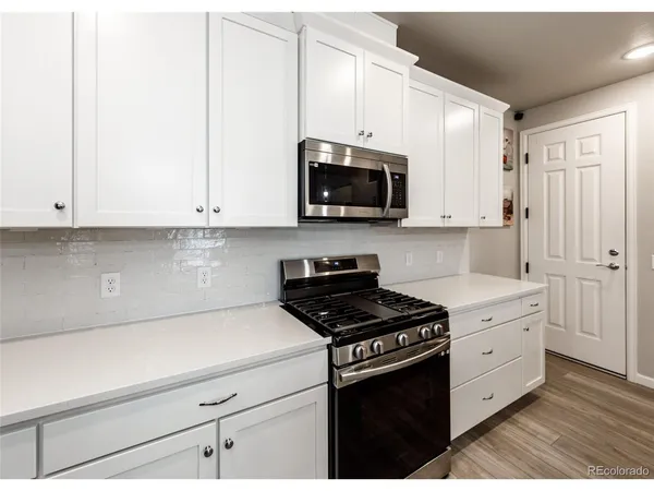 a kitchen with granite countertop white cabinets and black appliances