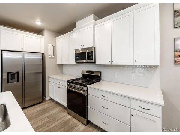 a kitchen with granite countertop white cabinets and stainless steel appliances