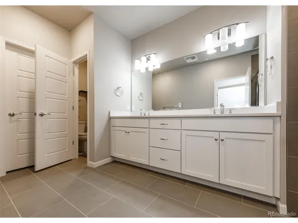 a spacious bathroom with a double vanity sink a mirror and a