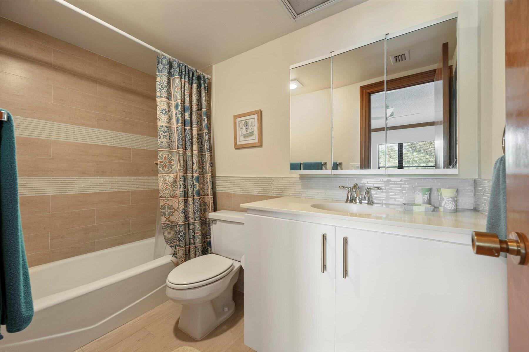 13244 Polo Club Road, Unit C207 Wellington, FL 33414 - Photo 11 of 31 a bathroom with a toilet a sink a mirror a bathtub and shower