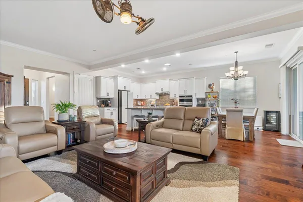 a living room with furniture kitchen view and a chandelier