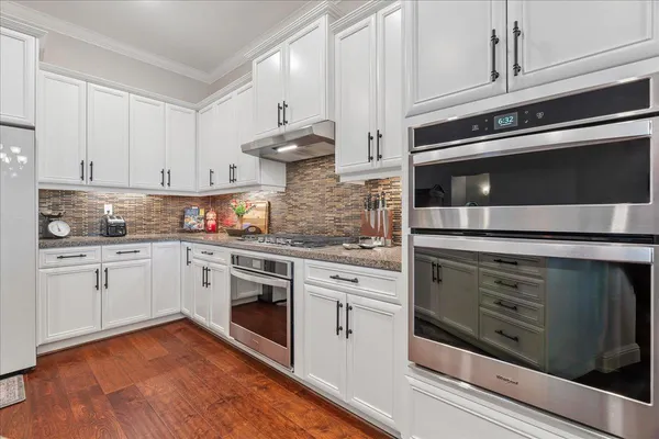 a kitchen with granite countertop white cabinets stainless steel appliances and sink