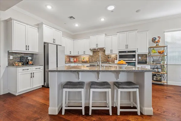 a kitchen with stainless steel appliances a table chairs refrigerator and microwave