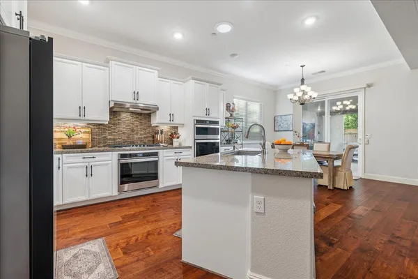 a kitchen with kitchen island granite countertop a sink cabinets and stainless steel appliances
